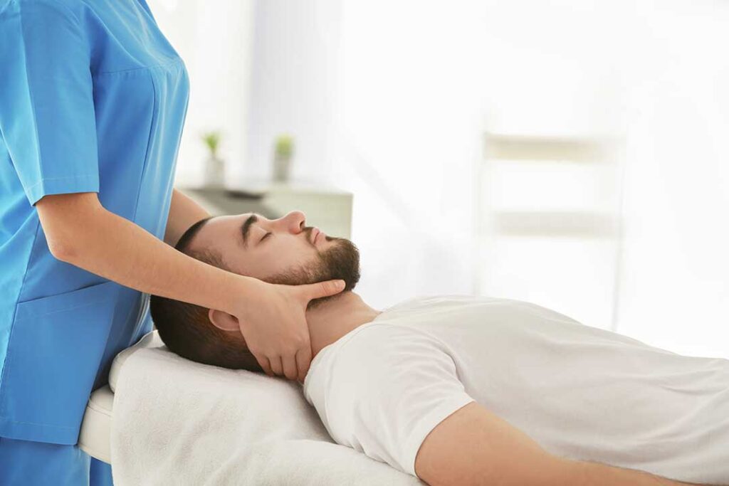 Person performing a gentle standing side stretch in a bright bedroom beside the bed.